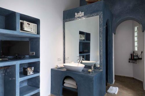 a blue bathroom with a sink and a mirror at Jack's Apartments & Suites in Essaouira