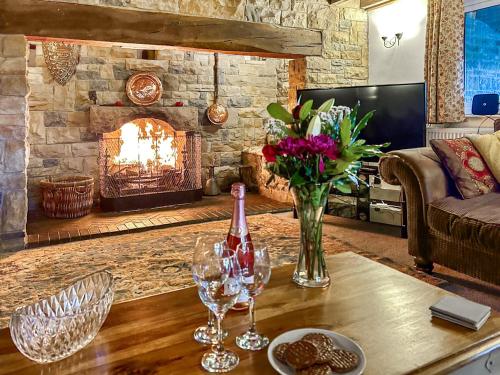 a living room with a table with wine glasses and a fireplace at Broadmeadows Farm in Butterton