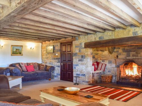 a living room with a fireplace and a stone wall at Broadmeadows Farm in Butterton