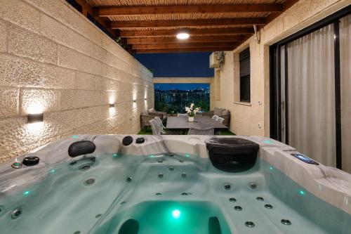 a jacuzzi tub in a room with a patio at GABRIEL APARTMENTS - Jacuzzi & Panoramic JLM View Steps to Shaare Zedek Hospital in Bayit Wegan