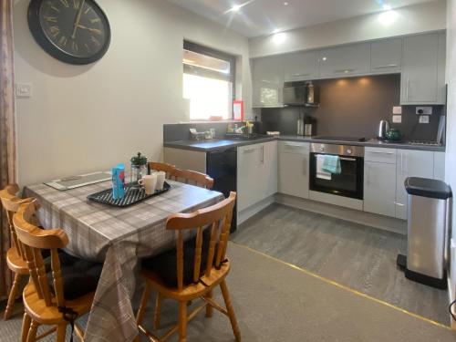 a kitchen with a table and a clock on the wall at Puffin - Dubh Segir in Lerags