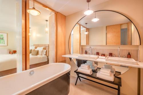 a bathroom with a tub and two sinks and a bed at Maison Honnel in Paris