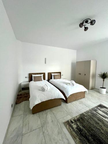 two beds in a bedroom with white walls at Casa Racolța Central Garden in Câmpia Turzii