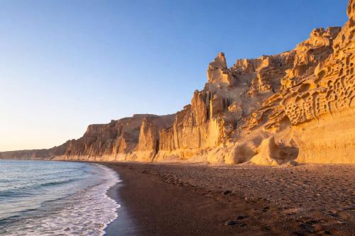 a view of a beach with rocky cliffs at Villa Therme Athen - Sea View Jacuzzi Santorini Stay in Emporio