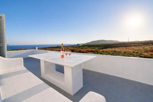 a white table with a bottle and two glasses on it at Villa Therme Athen - Sea View Jacuzzi Santorini Stay in Emporio