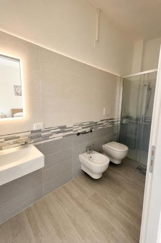 a bathroom with two sinks and a toilet and a mirror at La Finestra Sul Mare in Torretta