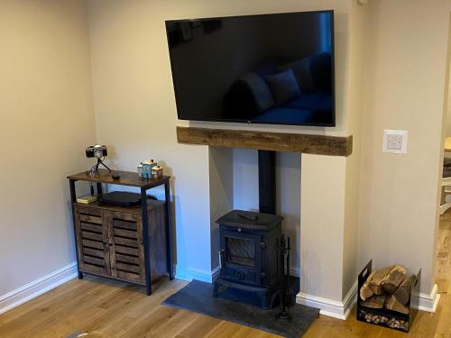 a living room with a fireplace and a flat screen tv at Lantern Cottage in Lyndhurst