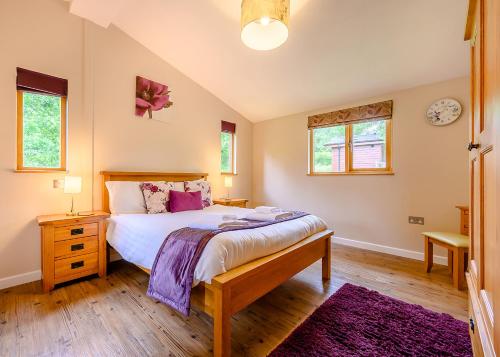 a bedroom with a large bed and two windows at Meadows End Lodges in Cartmel