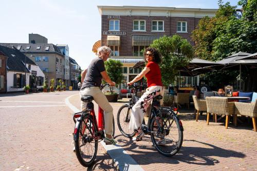 two people riding bikes down a street at Hotel de Wereld in Wageningen