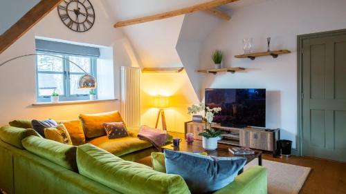 a living room with a green couch and a television at The Hayloft in Winchcombe