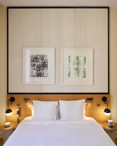 a bedroom with a white bed with two pictures on the wall at Maison Honnel in Paris