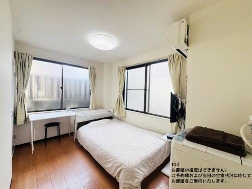 a bedroom with a bed and a desk and windows at SnowMapleHouse川口 in Kawaguchi