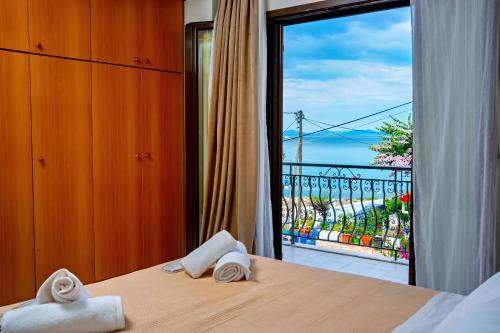 a bedroom with a balcony with a view of the ocean at Vythos Occidens in Plataria