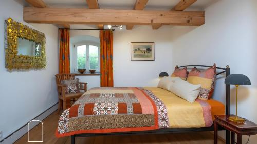 a bedroom with a bed and a chair and a window at Exklusives Gut Stohrerhof am See in Dießen am Ammersee