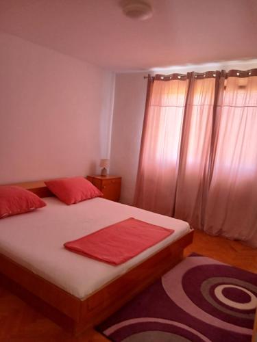 a bedroom with a bed with red pillows on it at Apartments Suzana in Čapljina