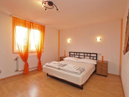 sypialnia z łóżkiem i oknem z pomarańczowymi zasłonami w obiekcie Apartments Denis 19 w Fažanie