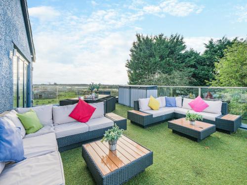 a patio with couches and a table with colorful pillows at North Plain Barn in Bowness-on-Solway