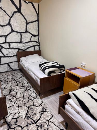 a bedroom with two beds and a stone wall at Artuch Camp - Fan Mountains in Yakkakhona