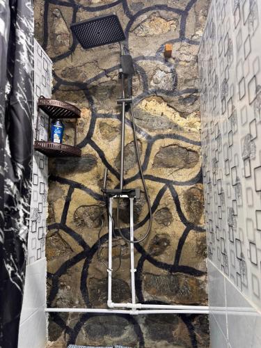 a shower in a bathroom with a stone wall at Artuch Camp - Fan Mountains in Yakkakhona