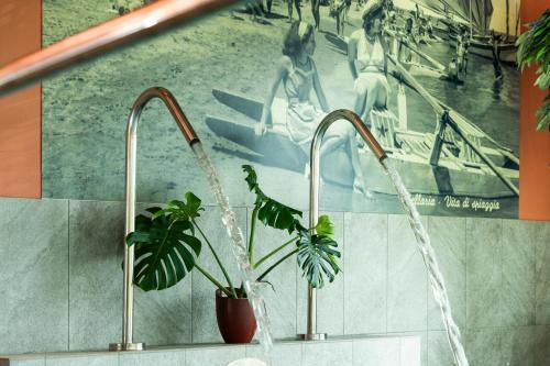 a bathroom with two faucets and a painting of a pool at Podere Luna Stella in Bellaria-Igea Marina