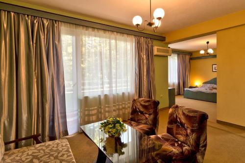een woonkamer met een tafel en stoelen en een raam bij Family Hotel Gabrovo in Gabrovo
