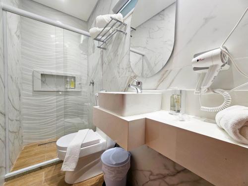 a white bathroom with a sink and a mirror at Opaba Praia Hotel in Ilhéus