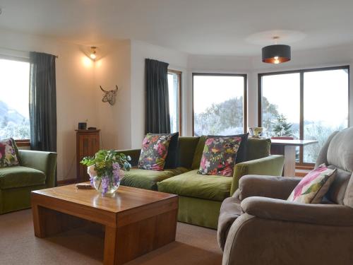 a living room with green couches and a coffee table at Cushendall House in Torcastle