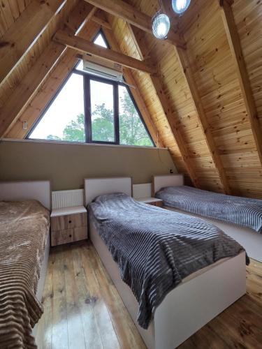 two beds in a attic bedroom with wooden ceilings at Villa ZM garden in Quba