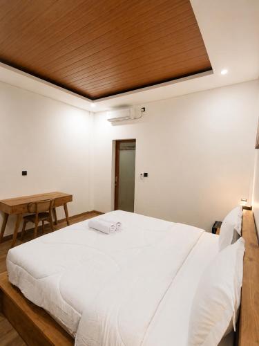 a bedroom with a large white bed with a wooden ceiling at Luling Guesthouse in Badung