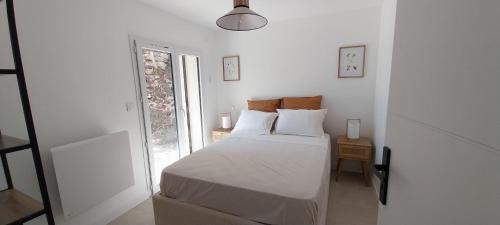 a white bedroom with a bed and a window at Le gîte de Coline in La Bridoire