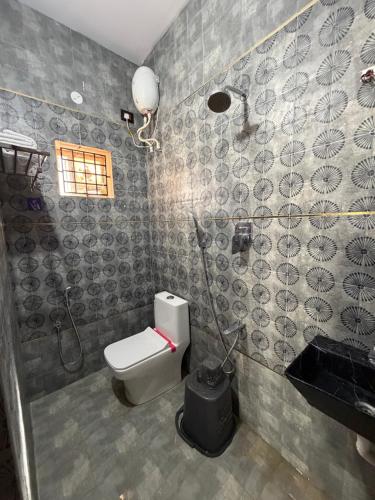 a bathroom with a toilet and a shower and a sink at Vihaalaya stays in Tozhuppedu