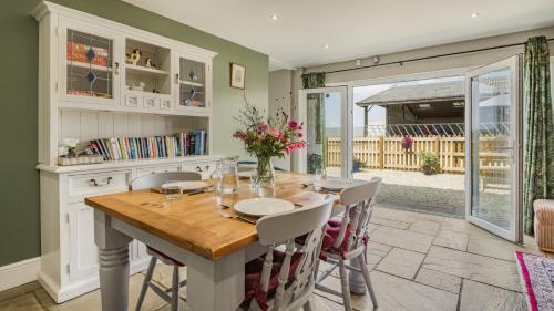 a dining room with a wooden table and chairs at Roe Barn in Sherston