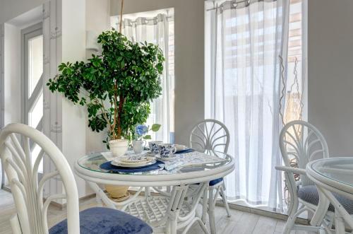 a white dining room table with chairs and a potted plant at Villa Pastelowa in Jastarnia