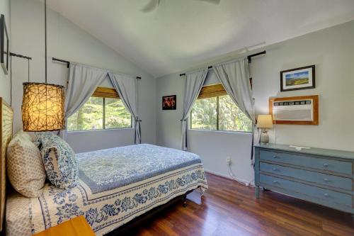 a bedroom with a bed and a dresser and two windows at Hale Ola Aina in Keaau