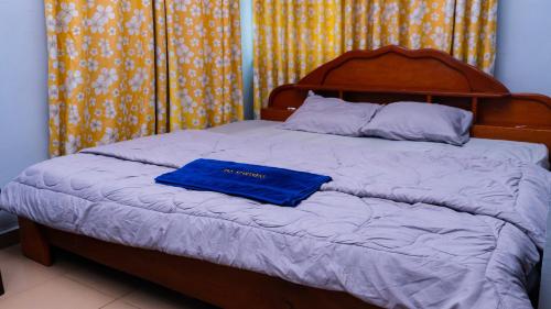 a bed with a wooden headboard and a blue towel on it at Jeks Apartments Limited in Ogbunike