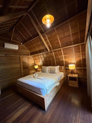 a bedroom with a bed in a wooden room at Jordan Guest House in Uluwatu