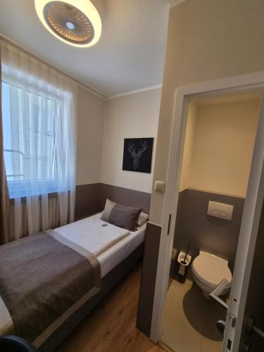 a small bedroom with a bed and a toilet at Hotel Italia in Munich