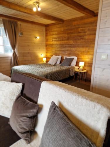 two beds in a room with wooden walls at Lukstas Rest Park in Graužai