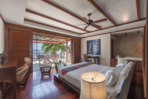 a bedroom with a bed and a desk and a balcony at Patong 4BR Seaview Villa with Infinity Pool in Patong Beach