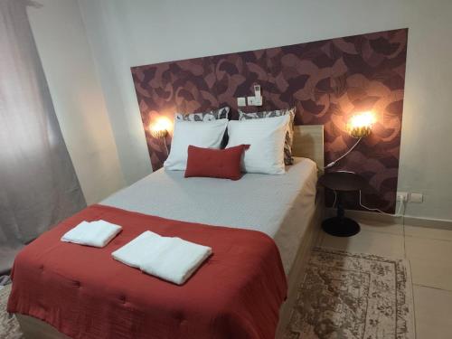 a bedroom with a bed with red blanket and white pillows at Hcp appartement in Abidjan