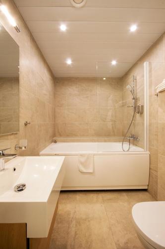 a bathroom with a tub and a sink and a toilet at MyApartments in Tallinn