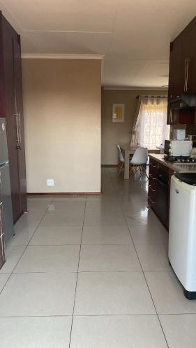 a kitchen with a large white tiled floor in a room at Tumi's Home away- 3 Bedroom in eMalahleni