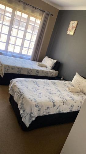 two beds in a bedroom with a window at Tumi's Home away- 3 Bedroom in eMalahleni