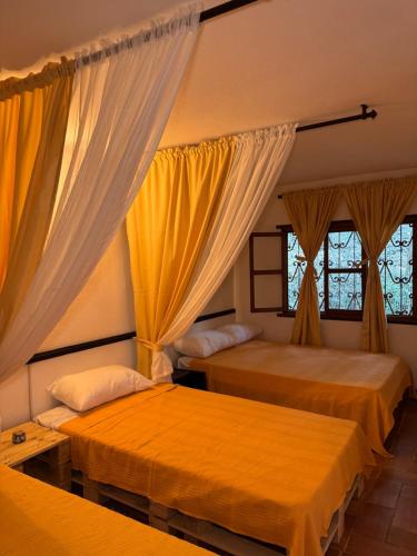 two beds in a room with yellow curtains at Hospedaje Casa Renasiente Cali in Cali