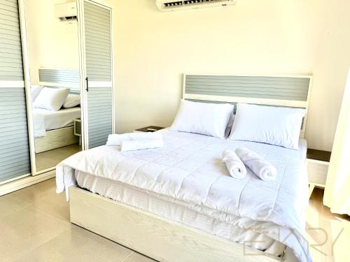 a bedroom with a white bed with towels on it at Gaia 2BR First Floor Apartment in El Dab‘a