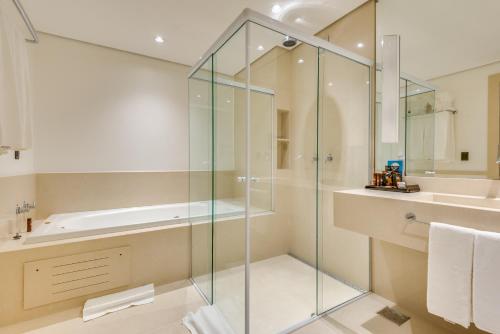 a glass shower in a bathroom with a tub and a sink at K Hotel in Goiânia