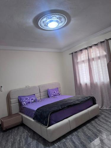 a bedroom with a bed with purple sheets and a ceiling at Tatkaba résidence in Conakry