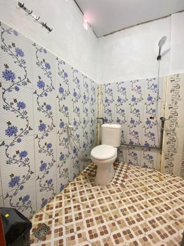 a bathroom with a toilet and blue and white tiles at Surak Villa Mentawai in Katiet