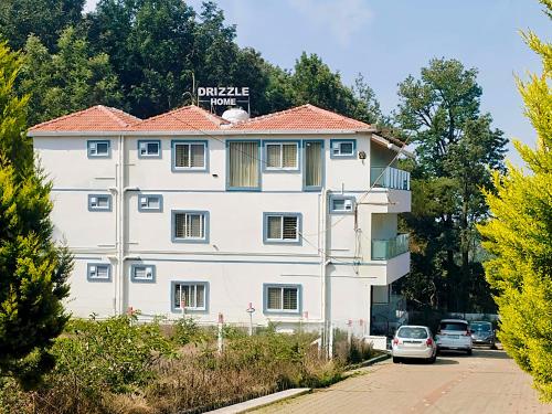 a white building with a sign on top of it at Drizzle Home - A Cosy Stay in Yercaud