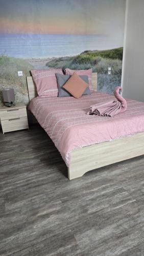 a bedroom with a large bed with pink sheets at Le Goeland in Beauvoir